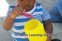 toddler posting small items into a container - grasp-release fine motor skills